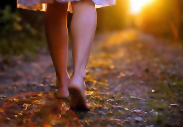 Imagem de Mulher caminhado de pés descalços numa rua de terra